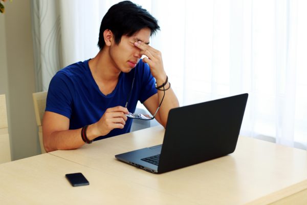 Asian man with computer made about the pop ups on his computer.