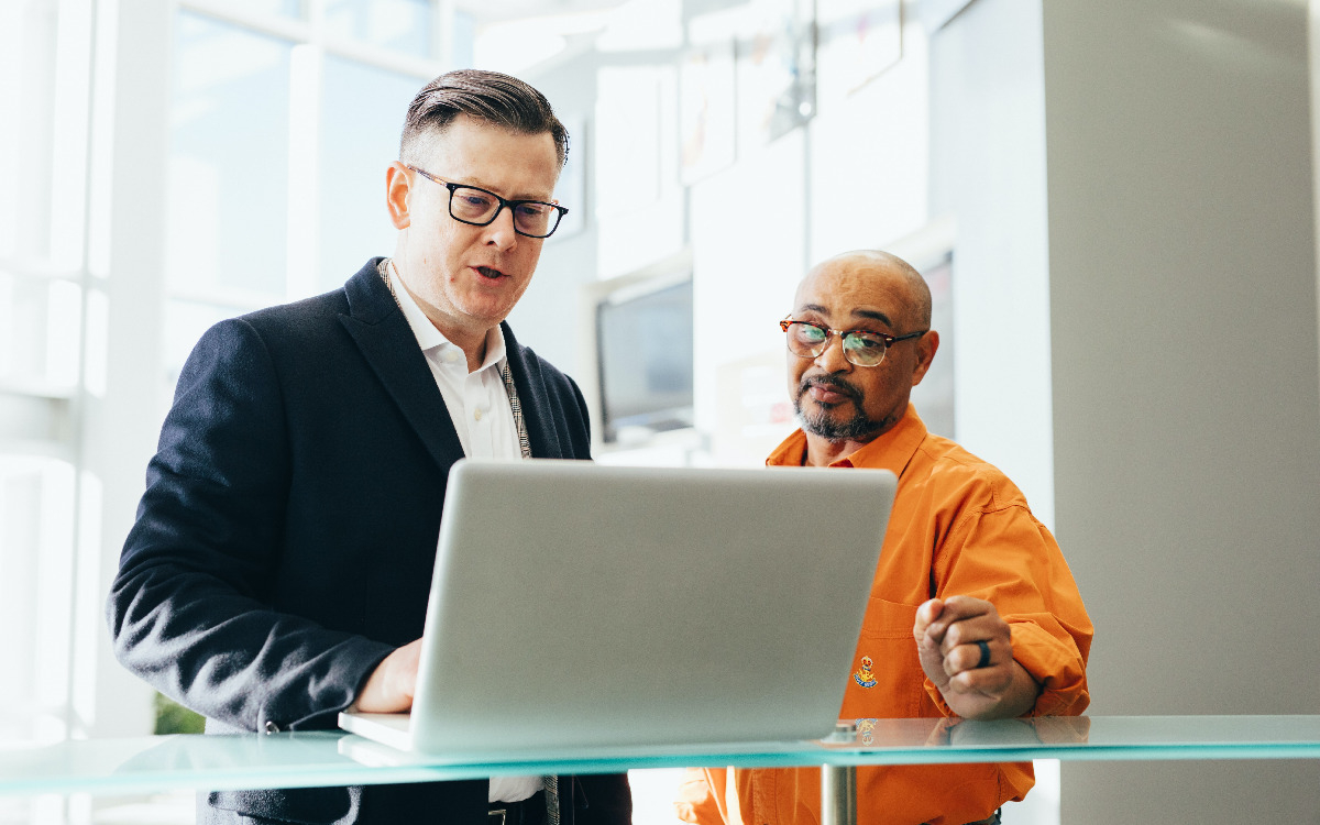 Specialist providing IT services to man using laptop