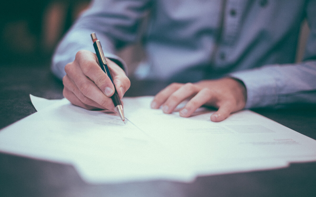 Man signing legal IT services document on table